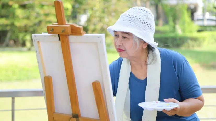 Woman having a hard time painting due to cataracts affecting how she sees colour.